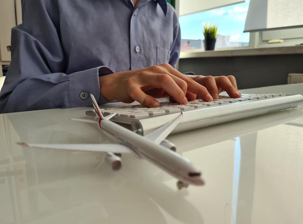 Travel agency owner emailing a client with a plane on their desk