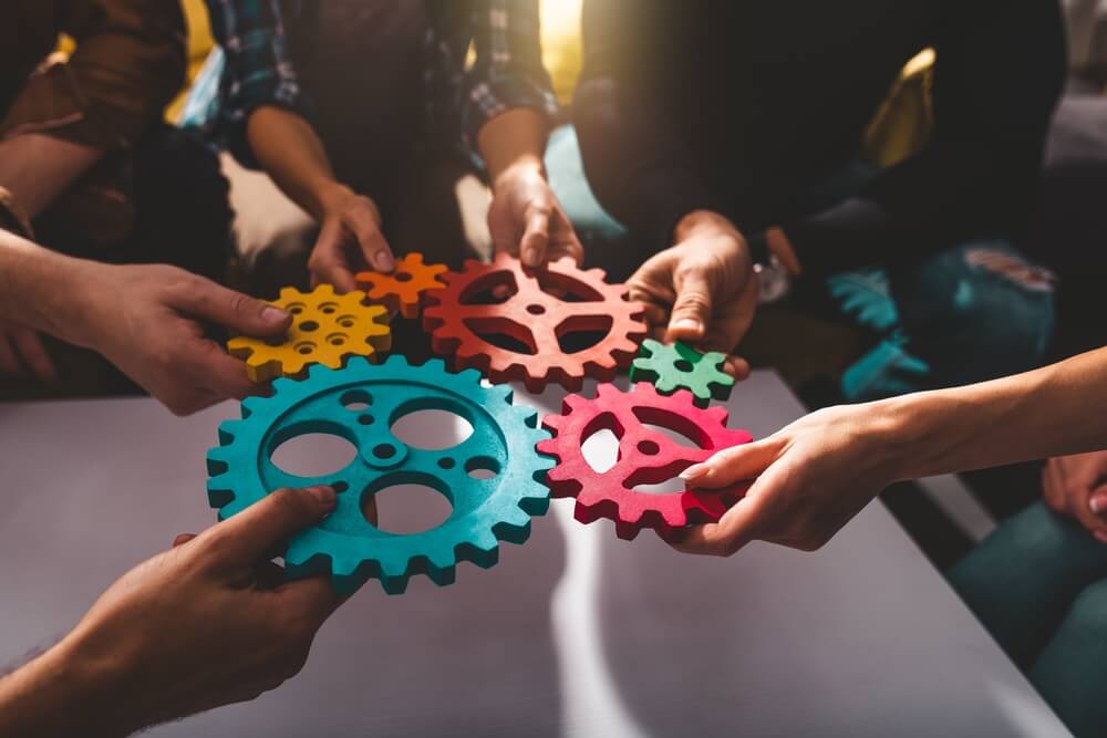 travel agency owners each holding a cog in a wheel